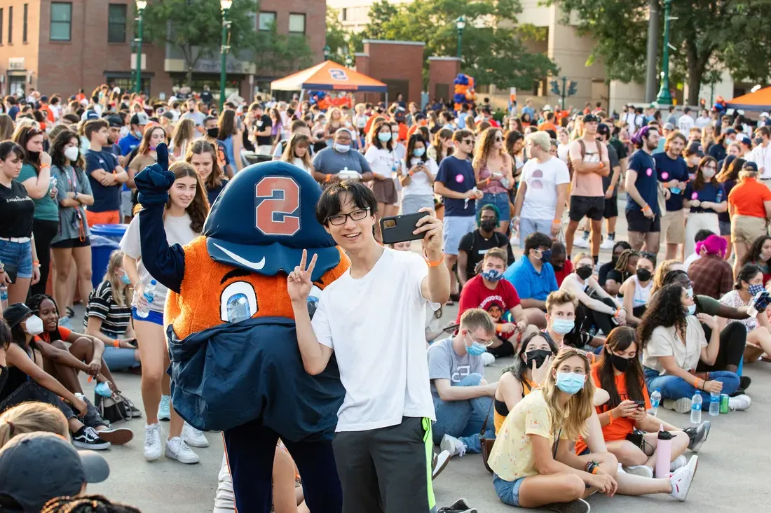 Student taking a selfie with Otto the Orange.